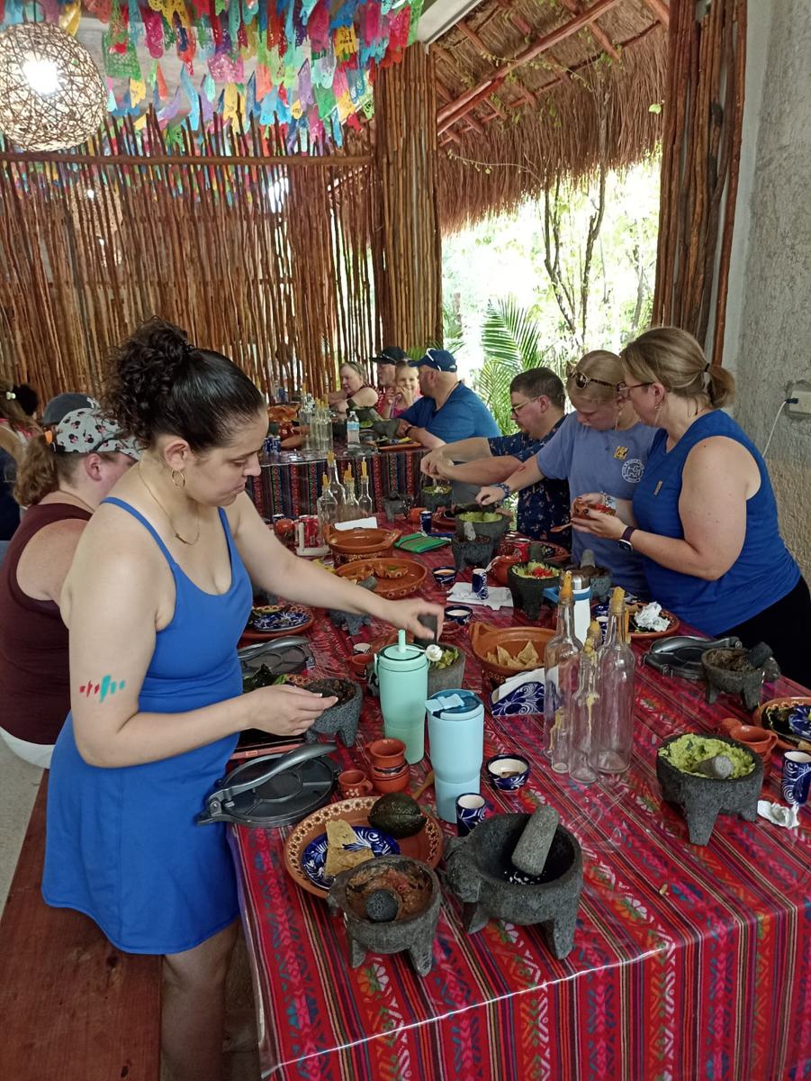 A guest grinding salsa in a molcajete at the long table