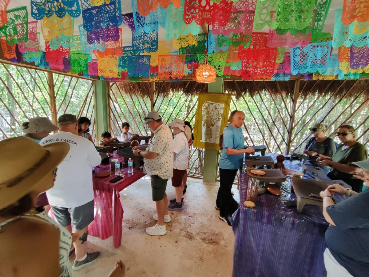 The cacao palapa full of guests grinding at stone tables