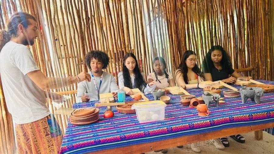 A guide talking to guests seated at a long table with small cups