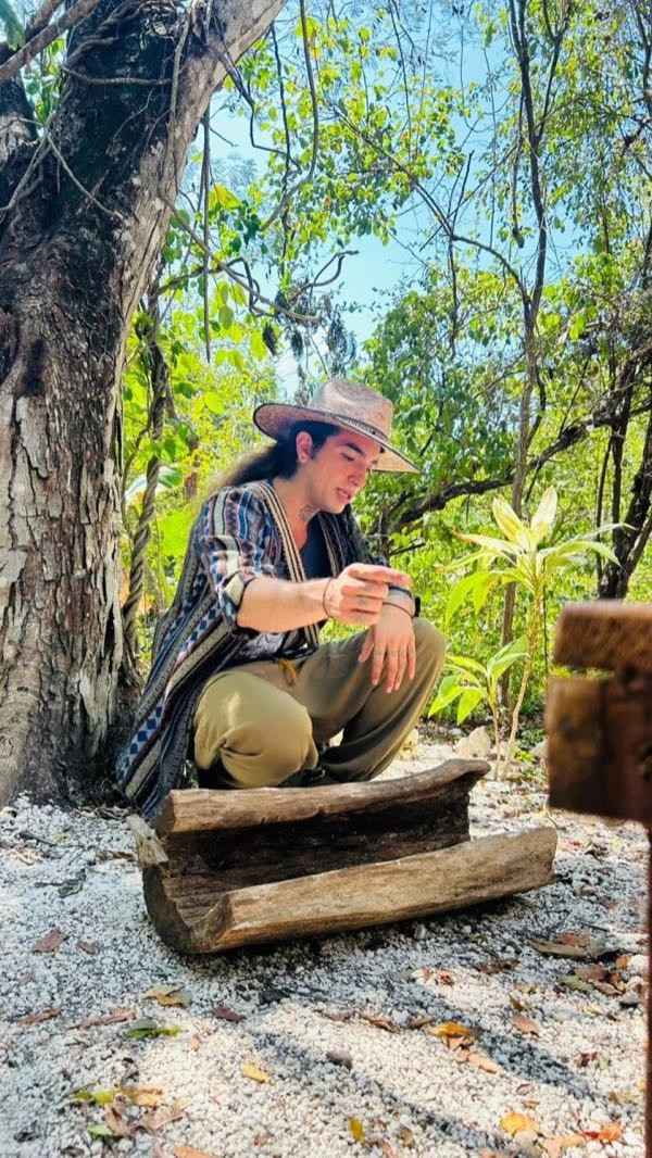 A guide crouched at a log in the jungle where the stingless bees live