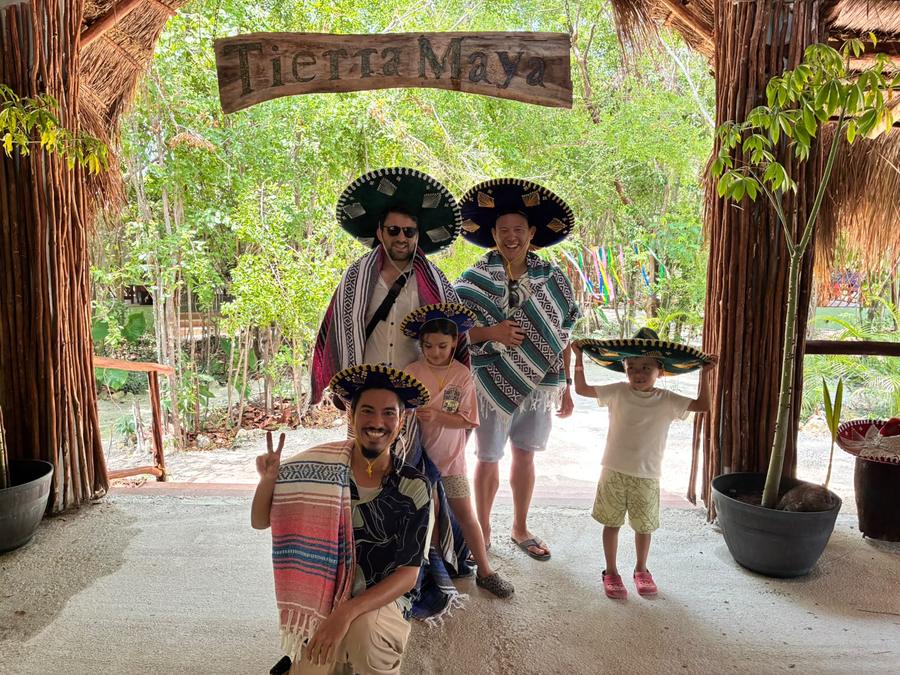 A family in charro sombreros and ponchos under the Tierra Maya sign