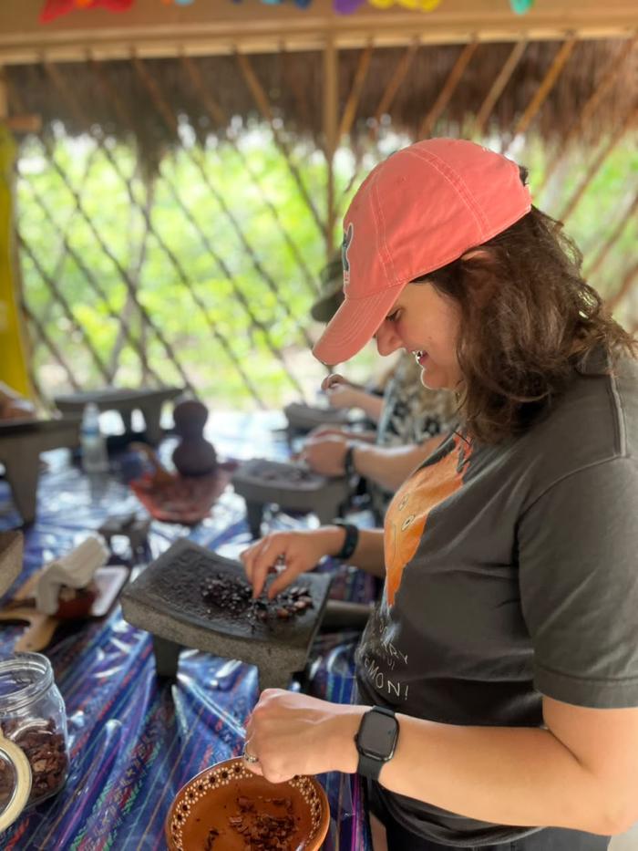 A guest grinding cacao, a clay cacao bowl in front