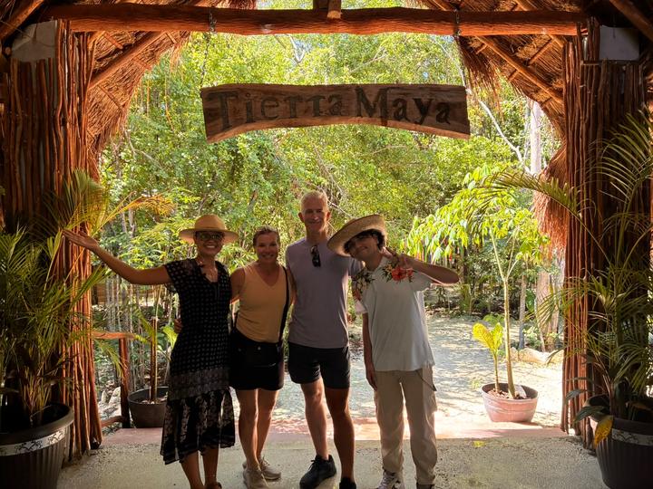 Four guests under the sign, arms out