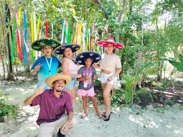 Family in charro sombreros under the ribbon trees, guide kneeling